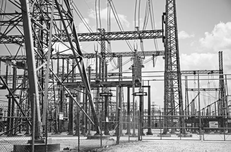 Black And White Photograph Of A Power Substation, Showcasing Electrical Equipment And Structures Against A Cloudy Sky