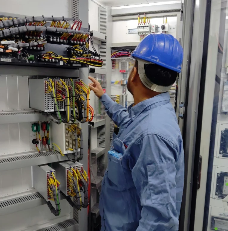 A Man In A Hard Hat And Blue Shirt Works Diligently On An Electrical Panel